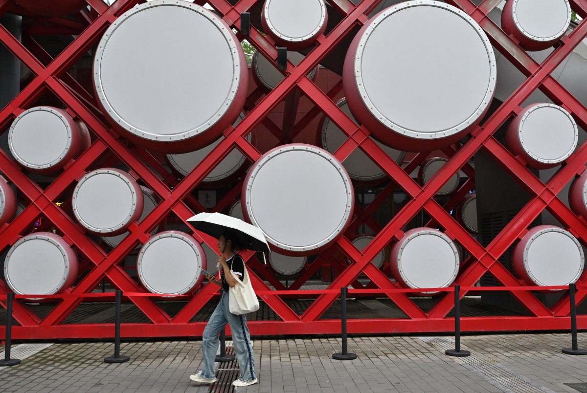 A woman walks by the Olympic park in Beijing on August 2, 2024. (Photo by ADEK BERRY / AFP)
