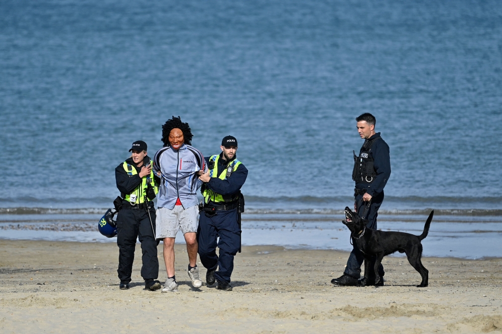 Police officers arrest a masked protester during the 'Enough is Enough' demonstration called by far-right activists in Weymouth, on the southwest coast of England where the Bibby Stockholm migrant accommodation barge is moored, on August 4, 2024. (Photo by Justin Tallis / AFP)