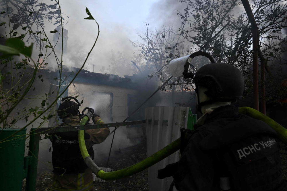 Ukrainian firefighters work to extinguish a fire in a private house that broke out a day after a missile attack in Myrnograd, Donetsk region, on August 21, 2024. (Photo by Genya SAVILOV / AFP)
