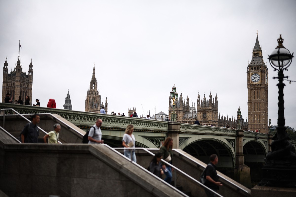 Pedestrians walk along the Southbank of the River Thames, with the Elizabeth Tower, commonly known by the name of the clock's bell 
