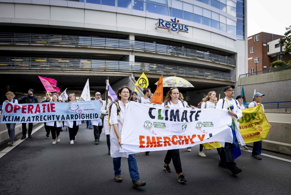 Extinction Rebellion (XR) activists hold a banner reading 