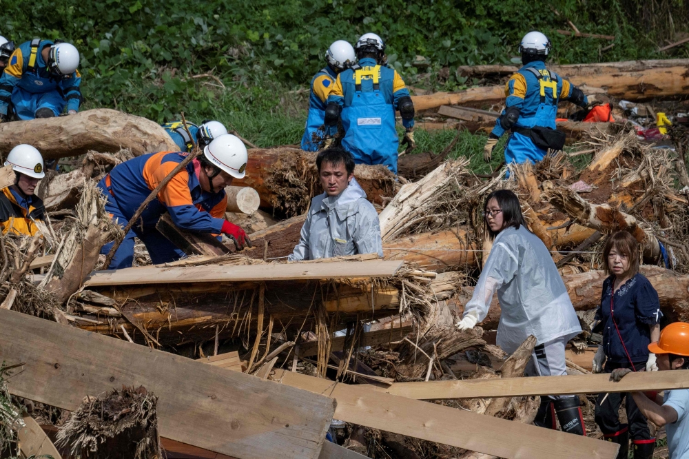 (Files) This file photo taken on September 23, 2024 shows Takaya Kiso (C) searching for his missing daughter among debris. (Photo by Yuichi Yamazaki / AFP)
 