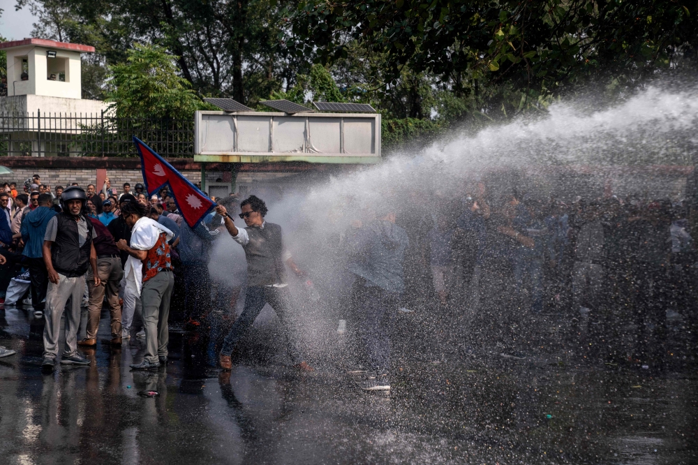 Police use water cannons to disperse supporters of Rabi Lamichhane, Nepal's former deputy premier, in Pokhara on October 20, 2024. (Photo by Yunish Gurung / AFP)