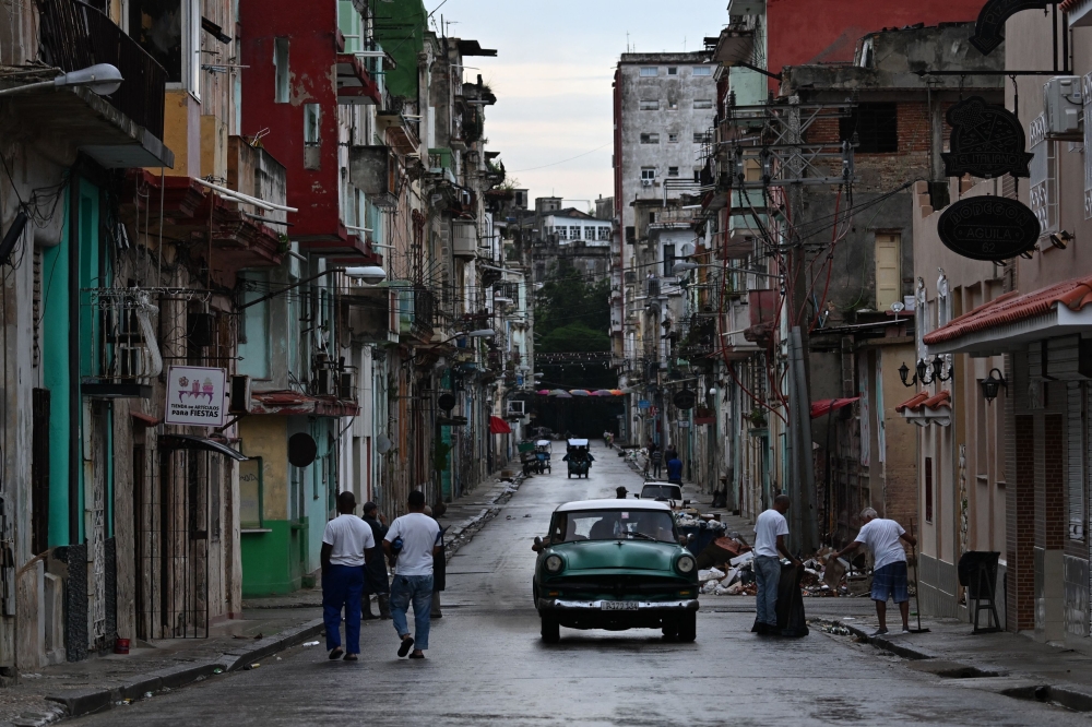 People walk along a street during the fourth day of a massive power outage in Havana on October 21, 2024. Photo by YAMIL LAGE / AFP