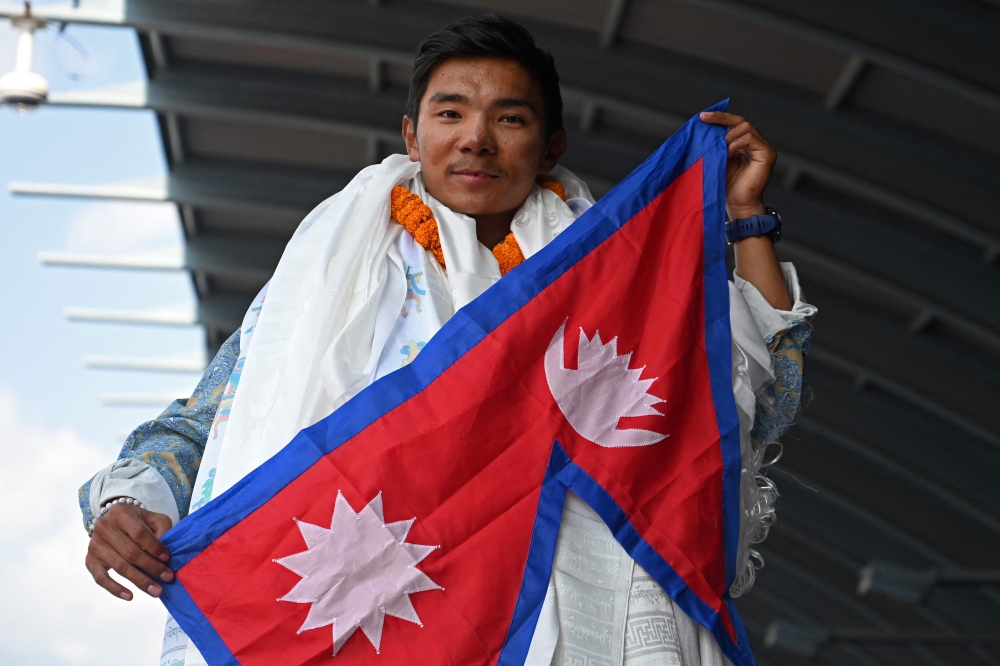 Nepali mountaineer Nima Rinji Sherpa poses upon his arrival at the airport in Kathmandu on October 14, 2024. Photo by Prakash MATHEMA / AFP

