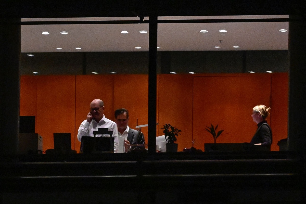 German Chancellor Olaf Scholz (L) is seen through the window speaking on the phone at the Chancellery with German Chief of Staff Wolfgang Schmidt (2nd L) in Berlin before a coalition committe meeting on November 6, 2024. (Photo by John MACDOUGALL / AFP)
