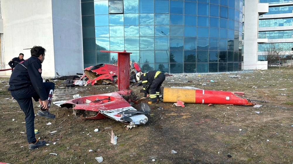 This handout photograph taken and released by the Demiroren News Agency (DHA) on December 22, 2024, shows rescuers looking at debris of a helicoper following a crash after it hit the fourth floor of a hospital in Mugla. (Photo by Handout / DHA (Demiroren News Agency) / AFP) 