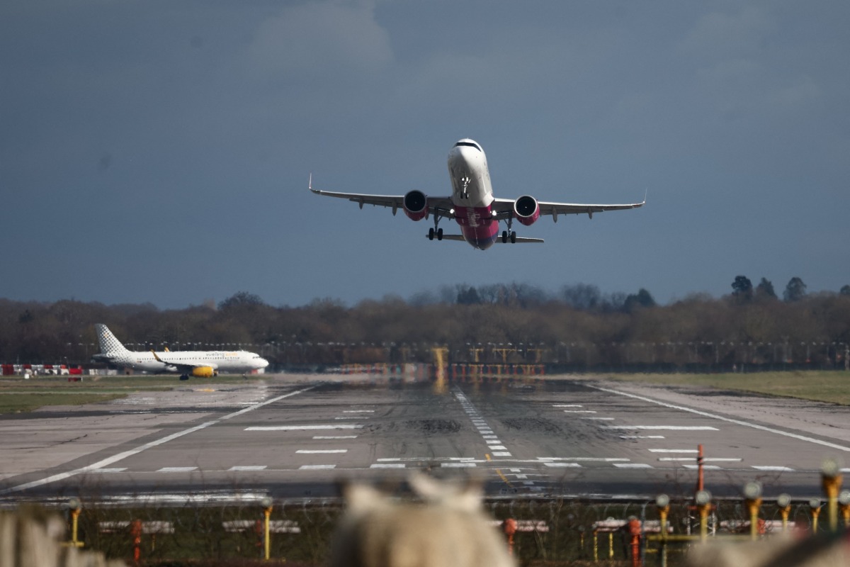 A passenger jet takes off from the single runway as another waits at Gatwick Airport, south of London on February 27, 2025, as the UK Government delay the final announcement on Gatwick's expansion until October. Photo by HENRY NICHOLLS / AFP