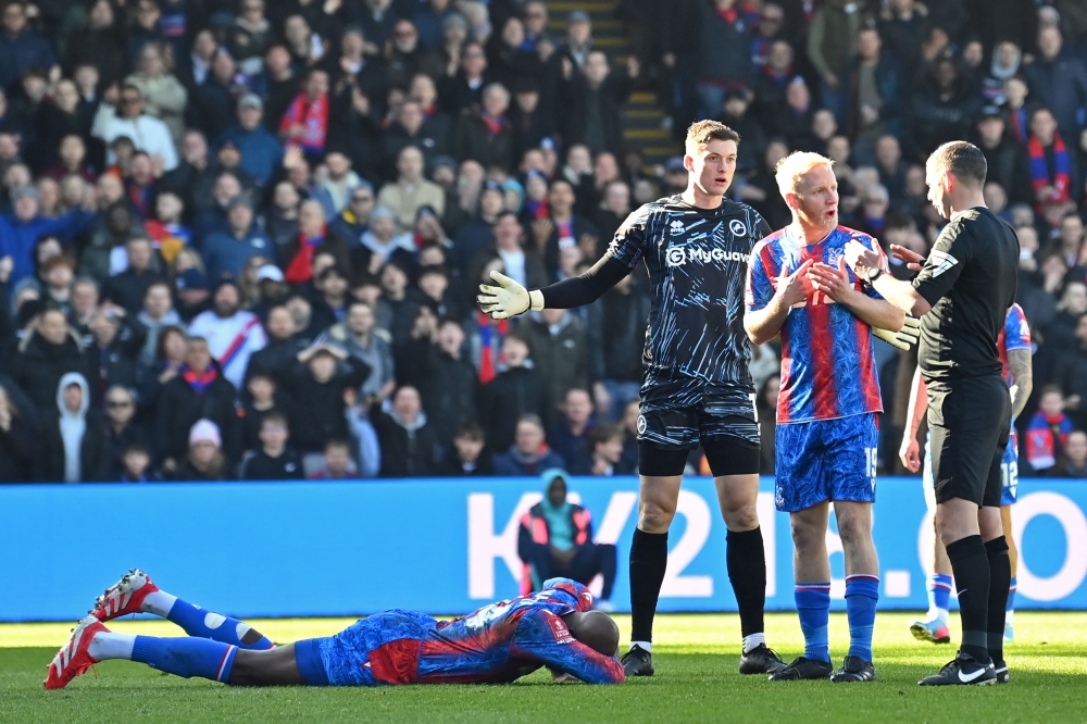 Crystal Palace's French striker #14 Jean-Philippe Mateta (L) lies injured after a dangerous challenge from Millwall's English goalkeeper #13 Liam Roberts (3R) in south London on March 1, 2025. (Photo by Glyn Kirk / AFP)

