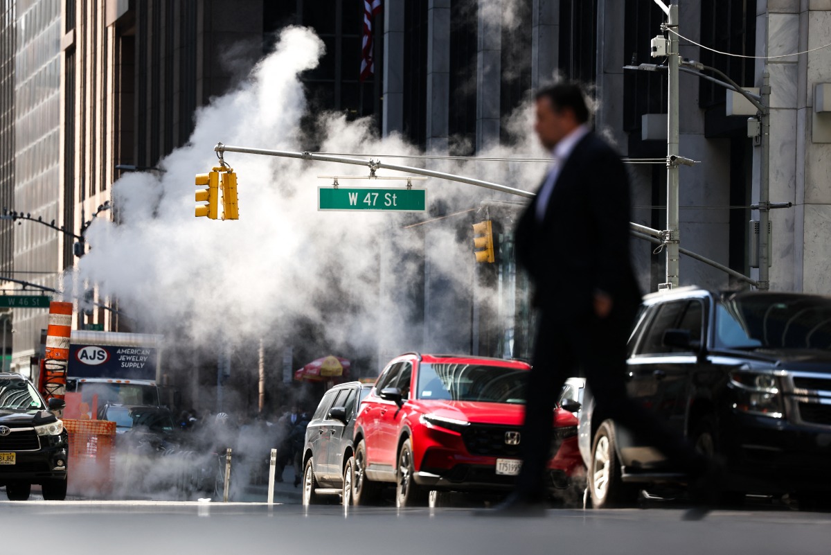 Steam rises from underground as pedestrians and cars move along the Sixth Avenue in the Manhattan borough of New York City on March 26, 2025. (Photo by CHARLY TRIBALLEAU / AFP)
