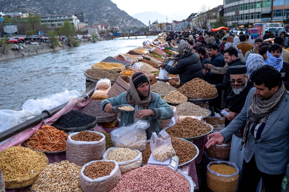 Afghans buy dry fruits along the Kabul river ahead of Eid Al Fitr, in downtown Kabul on March 27, 2025. (Photo by Wakil Kohsar / AFP)
