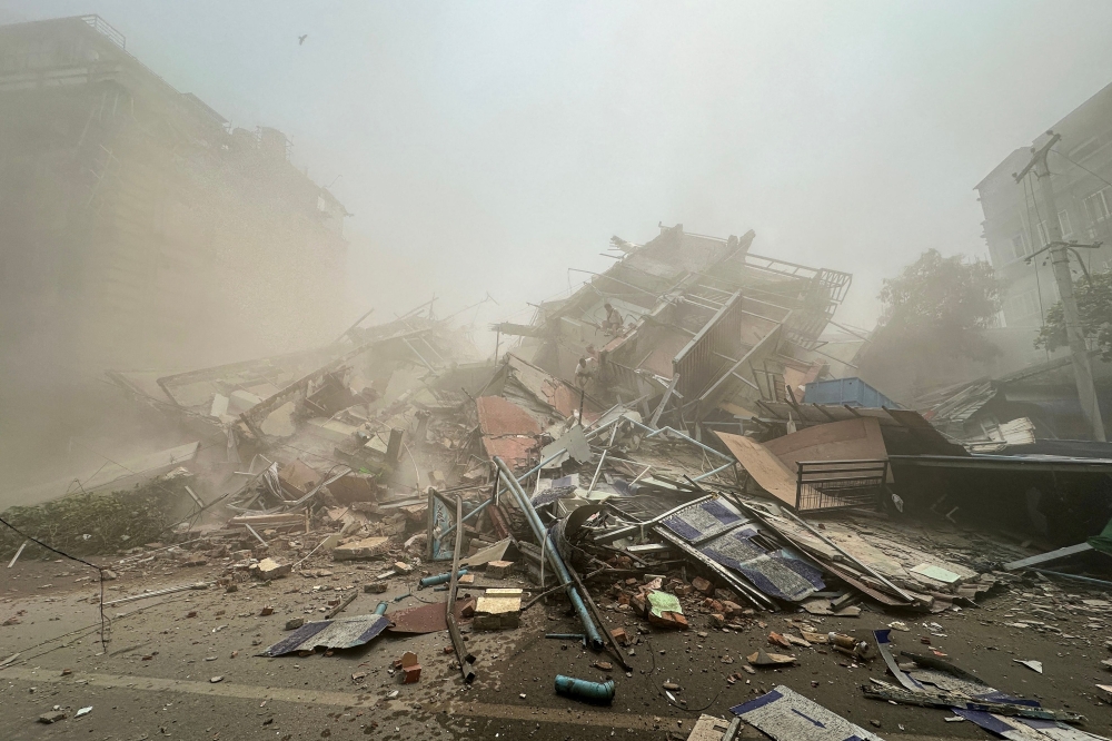 People inspect the debris of a collapsed building in Mandalay on March 28, 2025, after an earthquake. (Photo by AFP)


