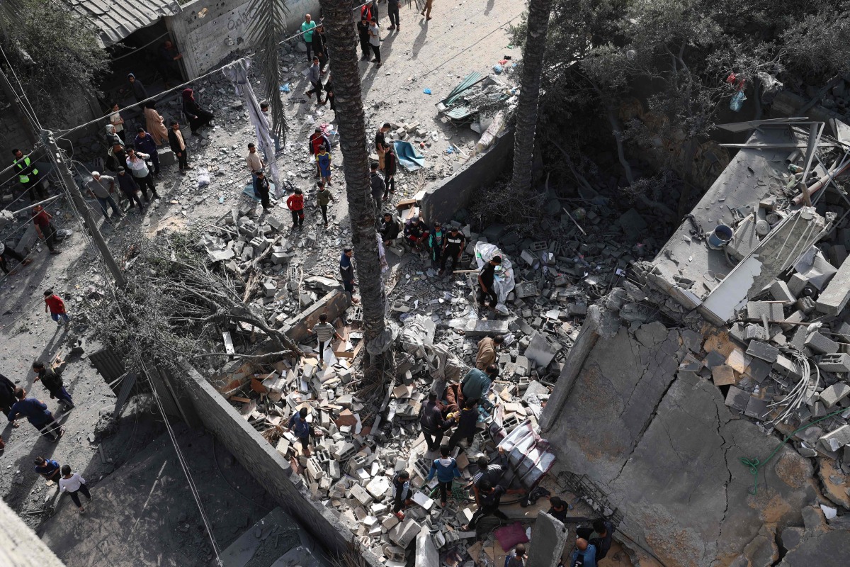 People inspect the destruction in a residential area in Deir al-Balah in the central Gaza Strip on April 7, 2025, following overnight Israeli airstrikes. (Photo by Eyad BABA / AFP)
