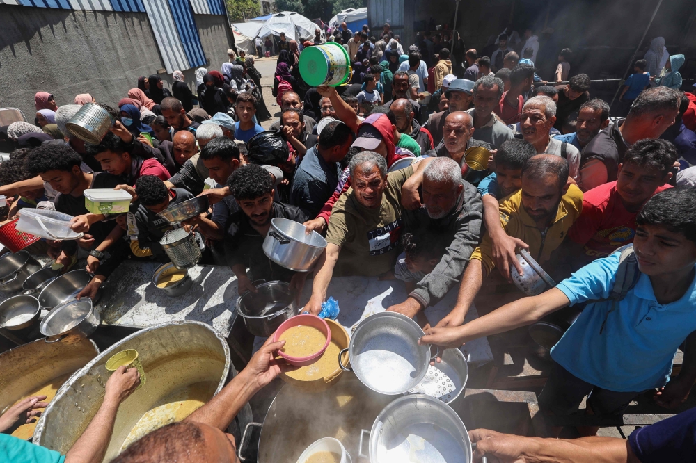 Palestinians queue for a hot meal at a charity kitchen run by the United Nation's World Food Programme (WFP) at the Nuseirat refugee camp in the central Gaza Strip on April 26, 2025. (Photo by Eyad Baba / AFP)