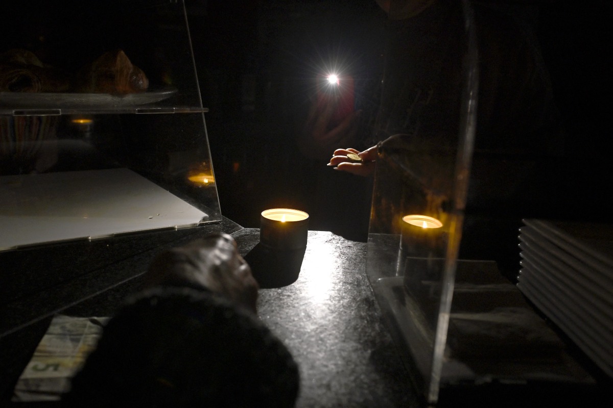 A waiter gives change by the light of her phone in a bar during a massive power cut affecting the entire Iberian peninsula and the south of France, in Hernani on April 28, 2025. (Photo by ANDER GILLENEA / AFP)
