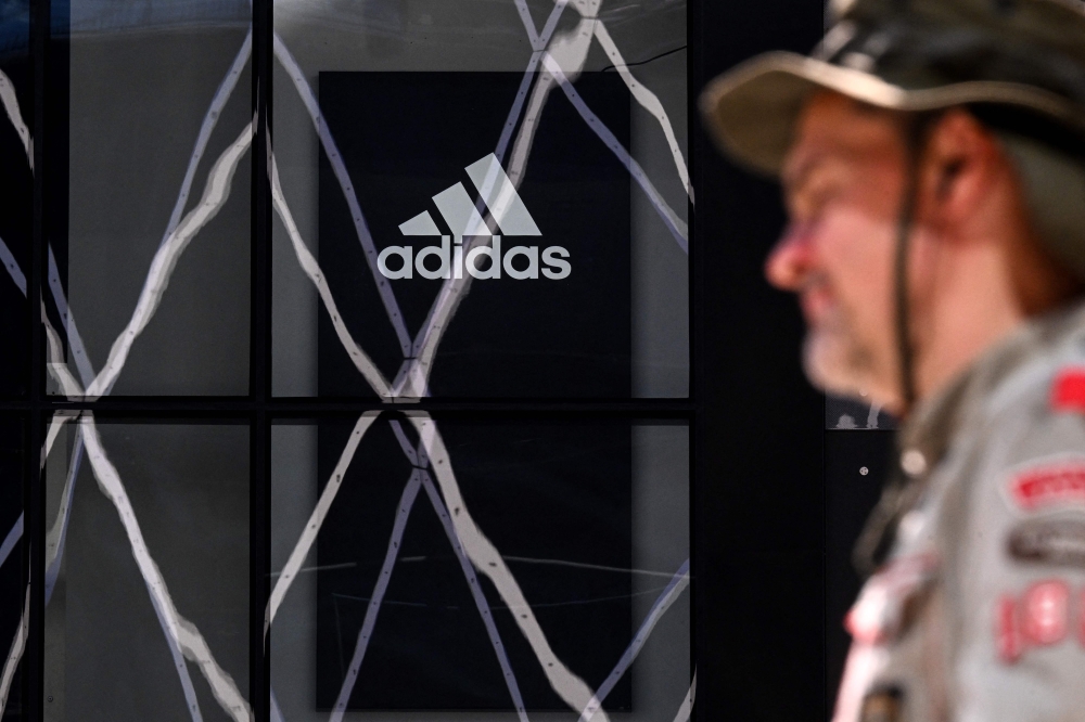 A person walks past a logo of sportswear giant Adidas on a shop wall in Frankfurt am Main, western Germany, on April 29, 2025. (Photo by Kirill Kudravtsev / AFP)