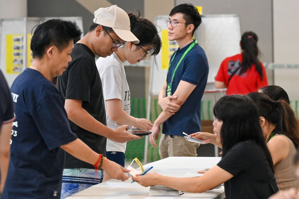 People register to vote in the general election at a polling station in Singapore on May 3, 2025. (Photo by Roslan Rahman / AFP)