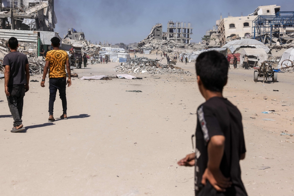 A Palestinian boy looks on as smoke billows following an Israeli drone strike in Jabalia, in the northern Gaza Strip on May 23, 2025. (Photo by Bashar Taleb / AFP)
 