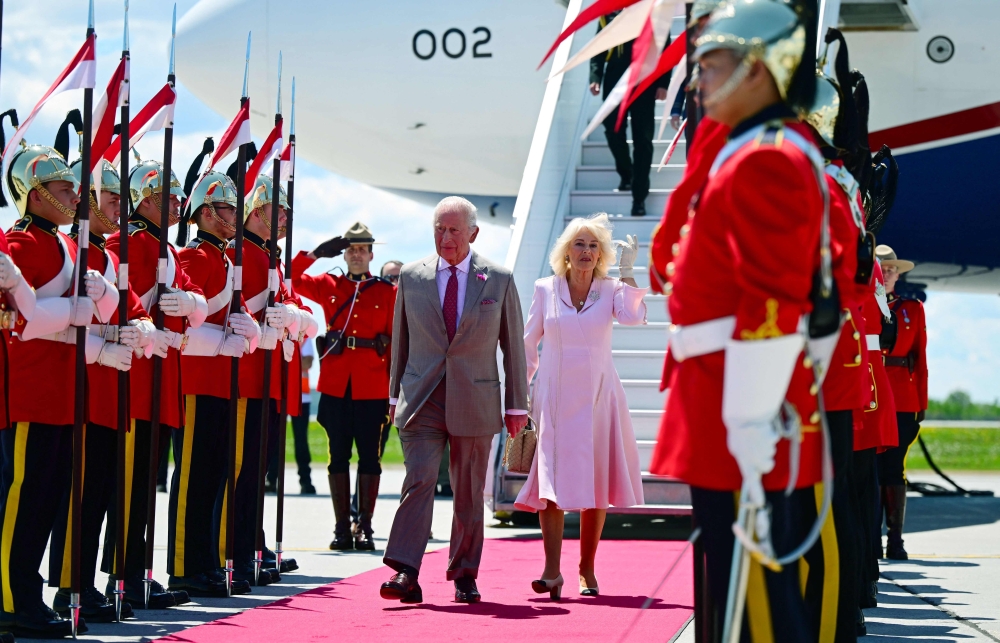 Britain's King Charles III and Britain's Queen Camilla are greeted by an honour guard after arriving at Macdonald-Cartier International Airport in Ottawa, Canada, May 26, 2025. (Photo by Victoria Jones / POOL / AFP)
