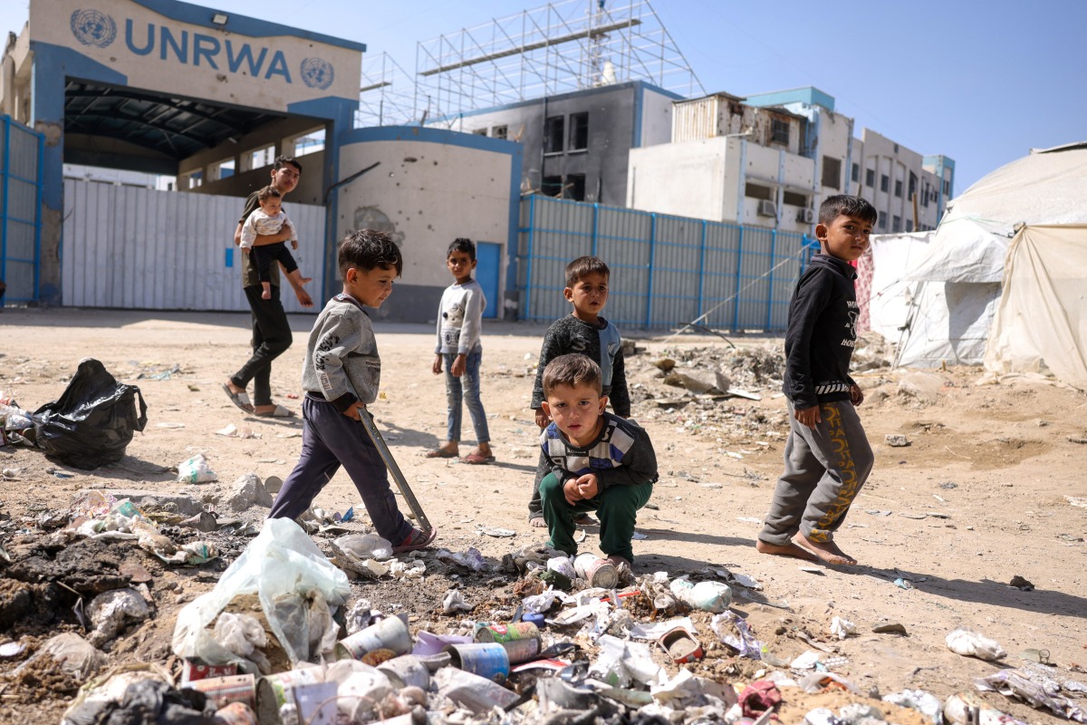 Children play around waste in front of the closed UN agency for Palestinian refugees UNRWA headquarters in Gaza City, on May 20, 2025. Photo by Bashar TALEB / AFP.
