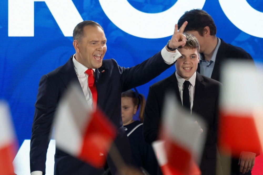 Karol Nawrocki, candidate for the 2025 Polish presidential election supported by Poland's right-wing Law and Justice (PiS) party, flashes the victory sign in front of supporters as exit polls were announced on tv during their election night event at the Mala Warszawa Theatre in Warsaw, Poland, during the second round of the presidential elections on June 1, 2025. (Photo by Wojtek Radwanski / AFP)