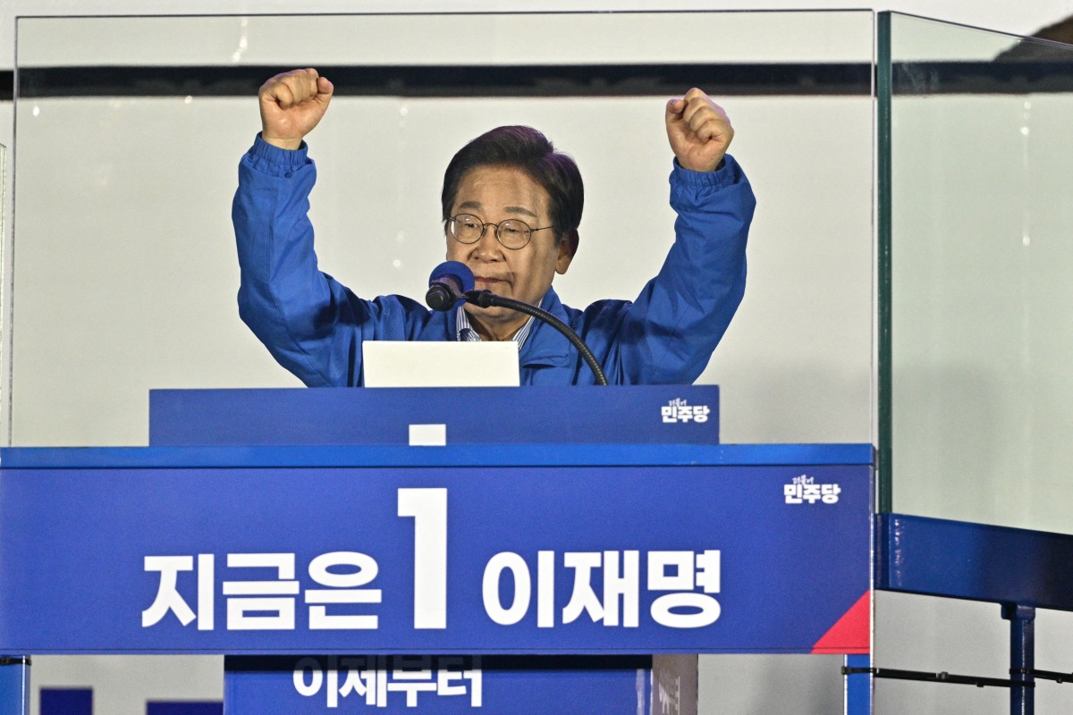 Lee Jae-myung, the presidential candidate for South Korea's Democratic Party, gestures behind bullet-resistant glass at the podium during his final election campaign event ahead of the upcoming June 3 presidential election in Seoul on June 2, 2025. Photo by ANTHONY WALLACE / AFP.