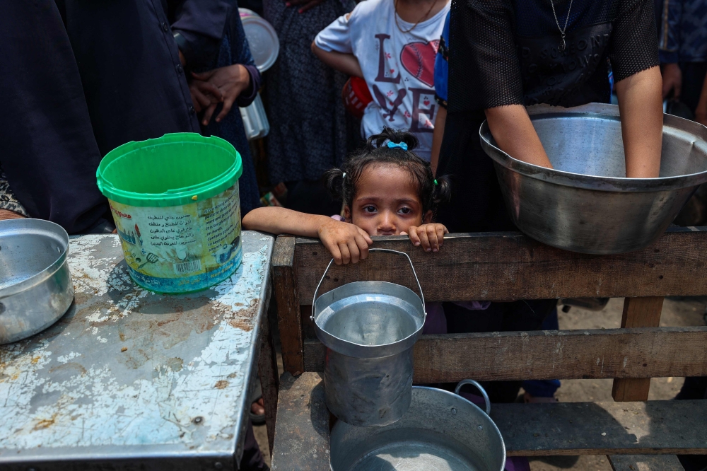 A girl waits with others to receive food at a distribution point in Nuseirat, central Gaza Strip, June 2, 2025. Israel has faced growing condemnation over the humanitarian crisis in the war-ravaged Gaza Strip, where the United Nations has warned the entire population faces the risk of famine after no aid was allowed to enter for more than two months. (Photo by Eyad Baba / AFP)