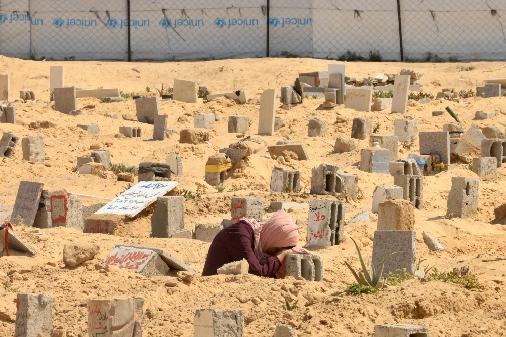 A Palestinian woman mourns over the grave of relative in Khan Yunis in the southern Gaza Strip on June 16, 2025.  (Photo by AFP)
