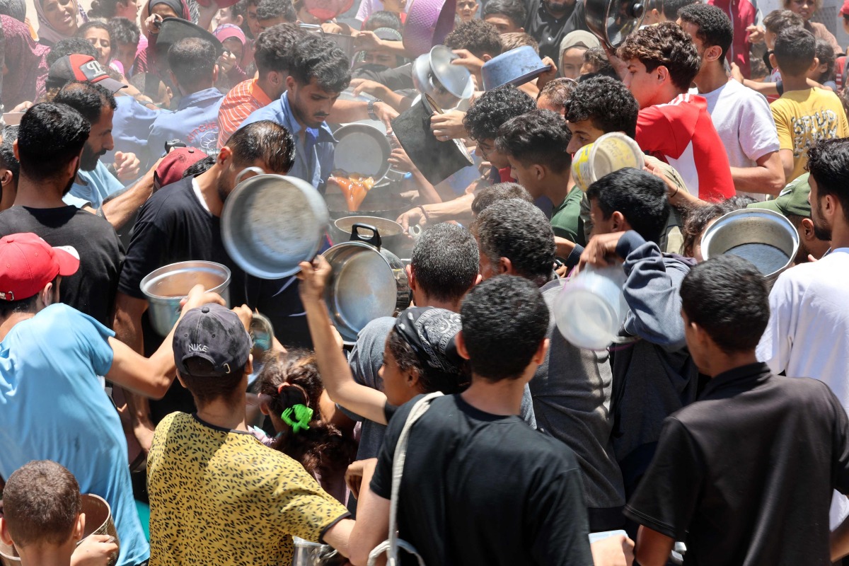 Palestinians try to get food at a charity kitchen providing hot meals in Rimal neighbourhood in Gaza City on June 18, 2025. Photo by Omar AL-QATTAA / AFP