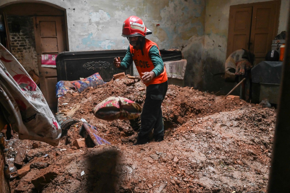 A rescue worker clears debris from a collapsed roof after heavy monsoon rains in Lahore on July 10, 2025 (Photo by Arif ALI / AFP)
