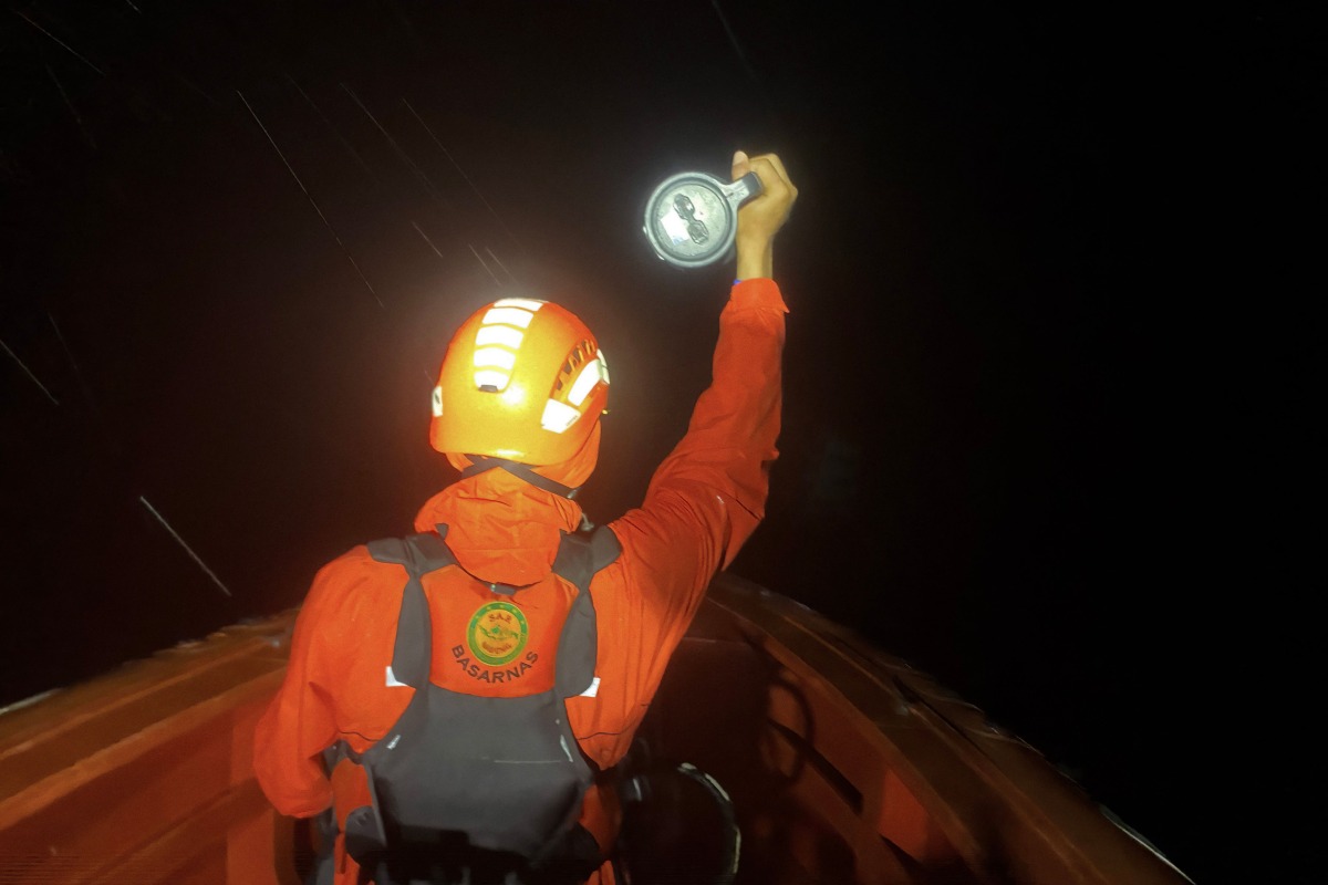This handout photo taken and released on July 15, 2025 by Indonesia's National Search and Rescue Agency shows a responder using a flashlight during the search for victims of a capsized boat in the waters off Mentawai Islands, West Sumatra. Photo by Handout / Indonesia's National Search and Rescue Agency / AFP