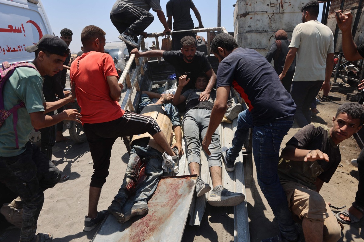 People transport men, wounded as he waited for humanitarian aid, along al-Rashid street in western Jabalia on June 22, 2025, after trucks carrying humanitarian aid entered the northern Gaza Strip through the Israeli-controlled Zikim border crossing. (Photo by Omar AL-QATTAA / AFP)
