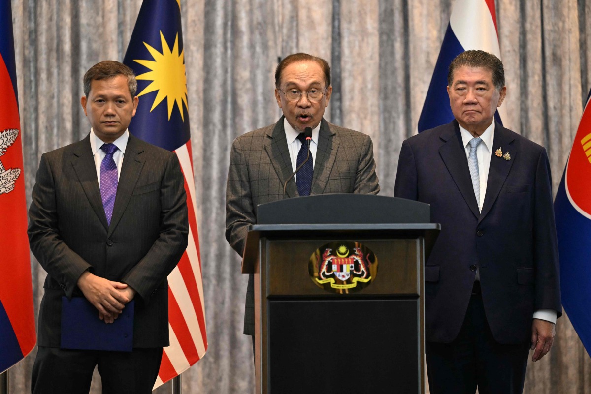 Malaysia's Prime Minister Anwar Ibrahim (C) speaks during a press conference next to Cambodia's Prime Minister Hun Manet (L) and Thailand's acting Prime Minister Phumtham Wechayachai (R) after talks on a possible ceasefire between Thailand and Cambodia in Putrajaya on July 28, 2025. Photo by MOHD RASFAN / POOL / AFP