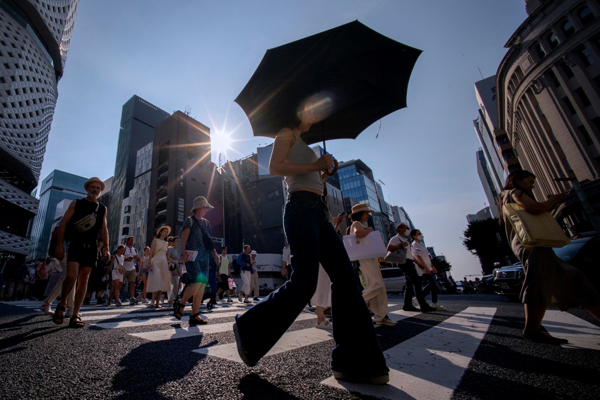 People cross a street on a hot day in Tokyo on August 4, 2025. Photo by Kazuhiro NOGI / AFP.