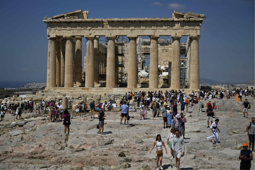  File: Tourists walk in front of the Parthenon Temple as they visit the Acropolis archaeological site in Athens on June 14, 2023. (Photo by Louisa Gouliamaki / AFP)
 