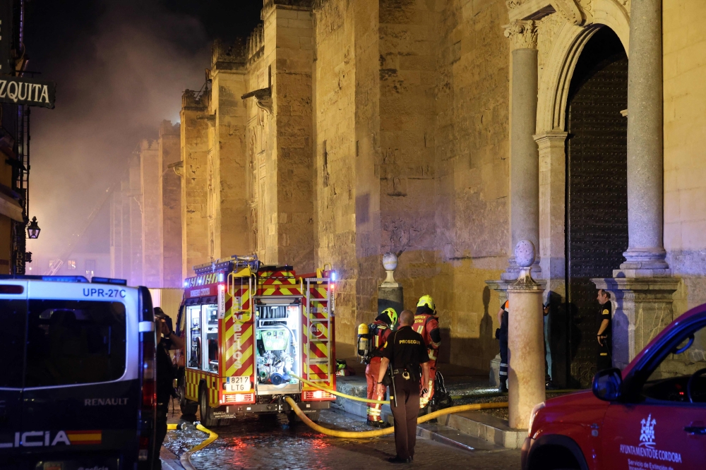 Firefighters work to extinguish a fire which broke out in the historic mosque-turned-cathedral in the southern Spanish city of Cordoba on August 8, 2025. (Photo by Madero Cubero / AFP)