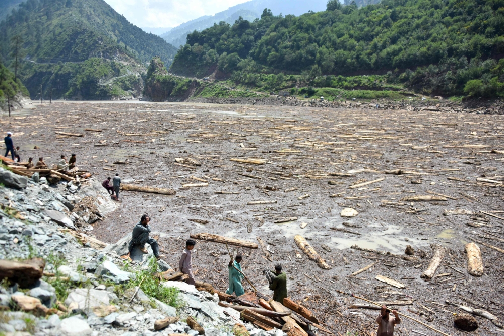 Locals collect woods from Noseri Dam near Muzaffarabad, the capital of Pakistan-administered Kashmir, on August 16, 2025. (Photo by Sajjad Qayyum / AFP)