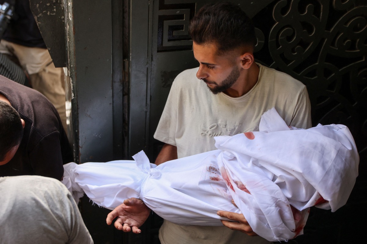 A Palestinian man carries the shrouded body of a child killed in Israeli strikes on Gaza City at dawn, during a funeral procession outside the Al-Shifa hospital on September 4, 2025, amid the war between Israel and the Hamas militant movement. (Photo by Omar AL-QATTAA / AFP)

