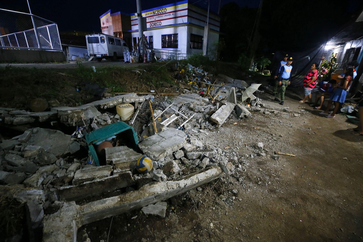 Police stand next to the rubble of a collapsed wall in Mati town, Davao Oriental province, in southern island of Mindanao, after a 7.4-magnitude earthquake struck the province. (Photo by Mark NAVALES / AFP)
