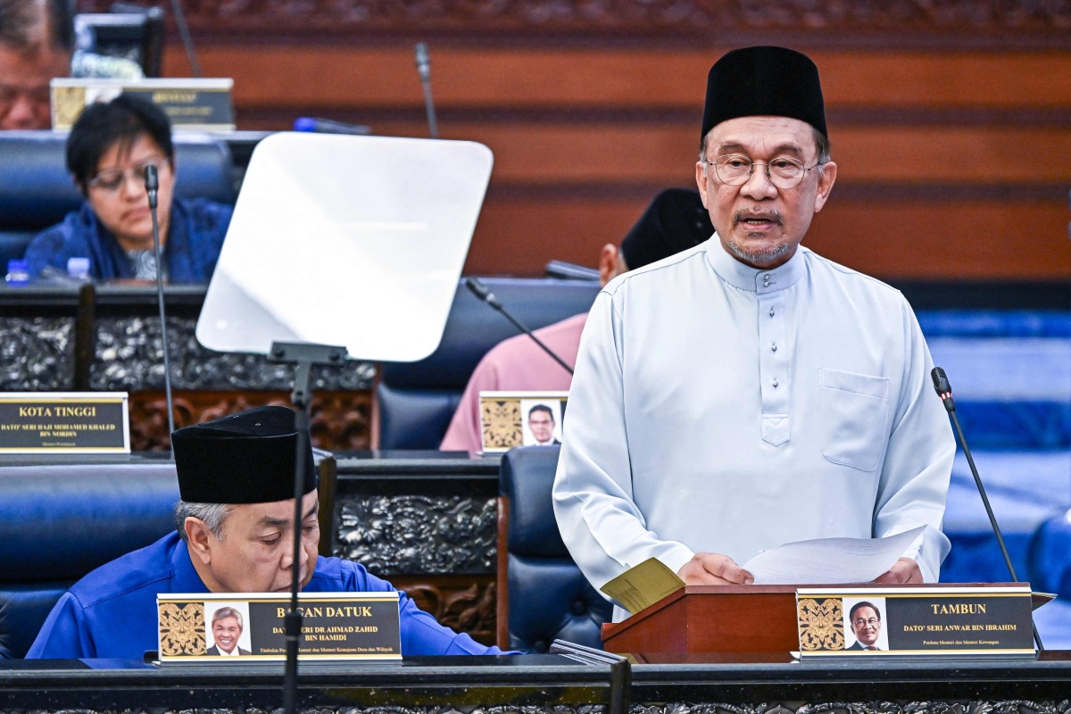 This handout photo taken and released by Malaysia's Department of Information on October 10, 2025 shows Malaysia's Prime Minister and Finance Minister Anwar Ibrahim delivering his speech on the 2026 national budget at the Parliament in Kuala Lumpur. (Photo by Nazri RAPAAI / DEPARTMENT OF INFORMATION / AFP