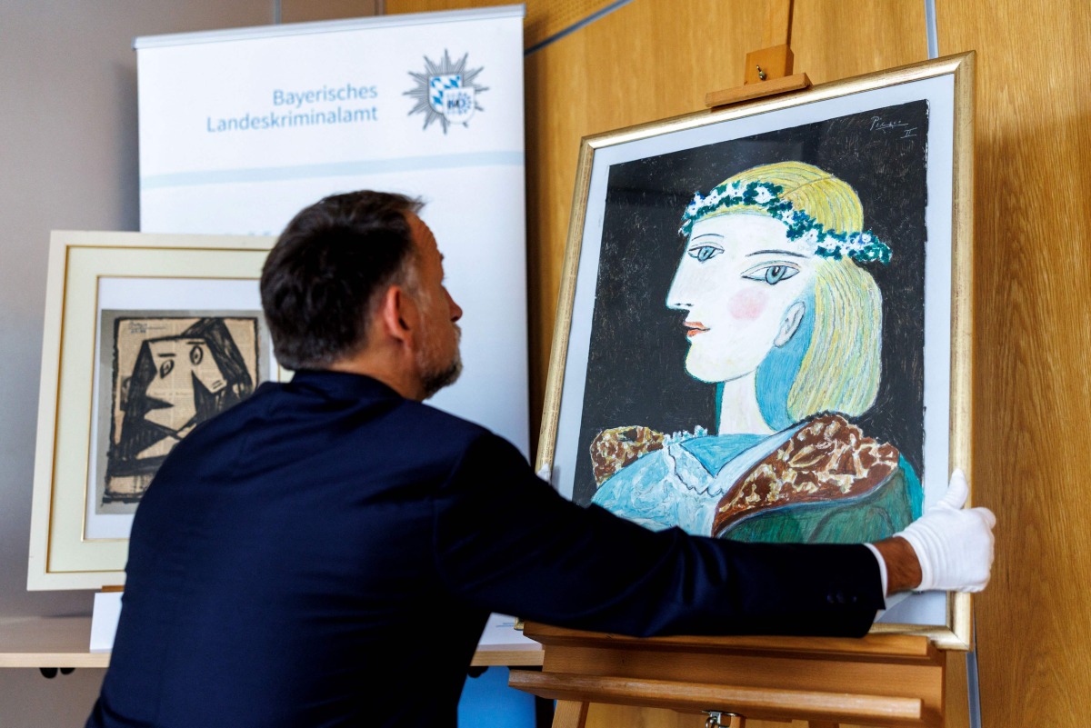 Patrick Haggenmueller, Head of the Art Investigation Unit of the Bavarian State Criminal Police Office (BLKA), displays the forged painting 'Portrait of Marie-Therese Walter with garland', offered as artwork by Spanish artist Pablo Picasso and confiscated by the police, during a presentation in the premises of the Bavarian State Criminal Investigation Department in Munich, southern Germany, on October 24, 2025. Photo by Matthias BALK / AFP