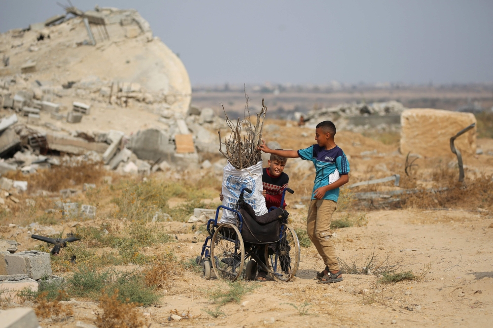Displaced Palestinian children collect branches and twigs to use for cooking amid fuel shortage in the village of Juhr al-Dik, east of the Bureij refugee camp in the central Gaza Strip, on November 3, 2025. (Photo by Eyad Baba / AFP)
