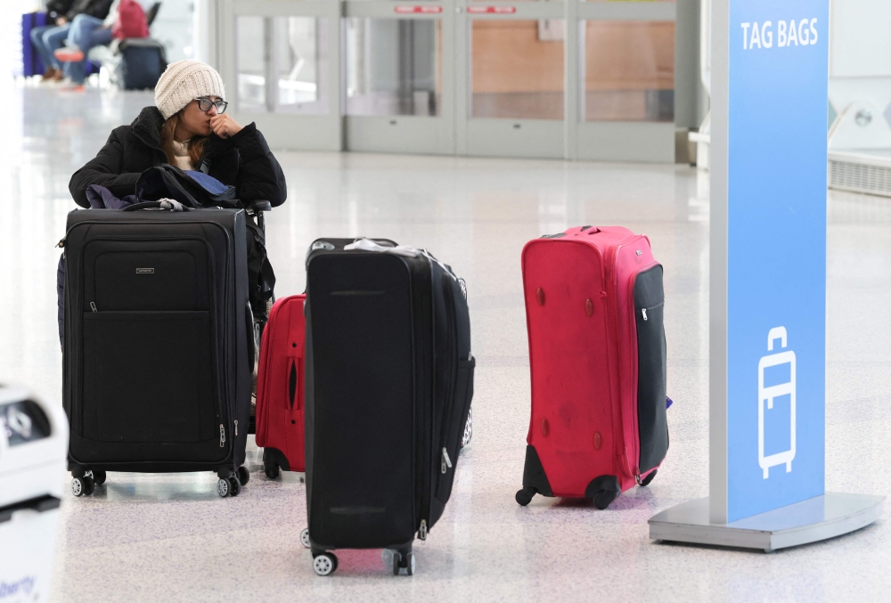 A traveler waits with her luggage at Newark Liberty International Airport in Newark, New Jersey, on November 7, 2025. (Photo by Timothy A. Clary / AFP)