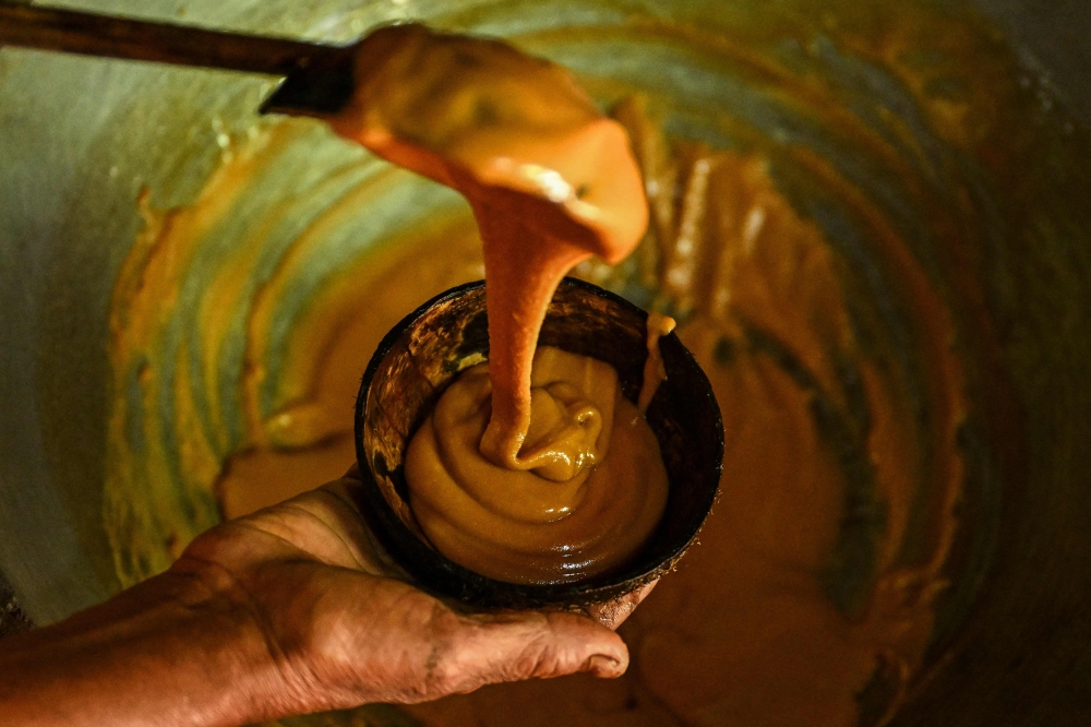 Sarath Ananda, a kithul tapper serving freshly-made jaggery from the kithul sap, at Ambegoda village in southern Sri Lanka. (Photo by Ishara S. Kodikara / AFP) /