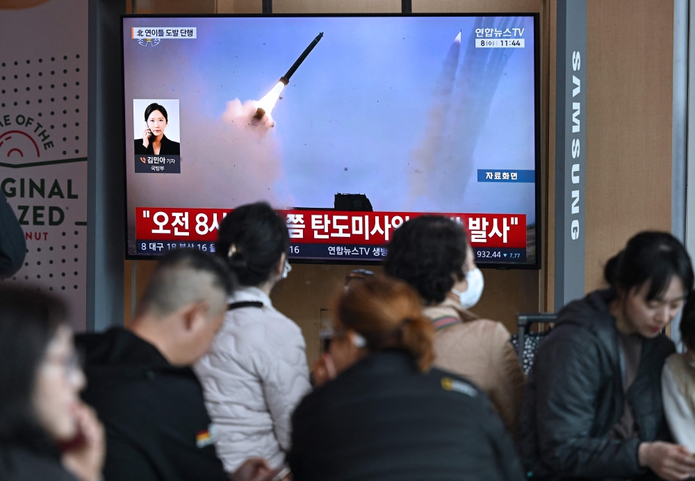 People watch a television screen showing a news broadcast with file footage of a North Korean missile test, at a train station in Seoul on April 8, 2026. (Photo by Jung Yeon-je / AFP)