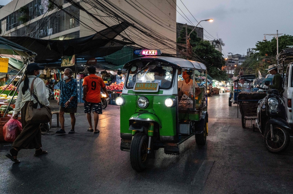 A tuk tuk drives past fruit stalls at Mahanak Market in Bangkok. (Photo by Anthony Wallace/ AFP)