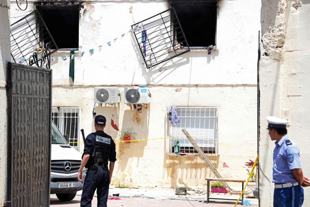 Police officers stand guard at the entrance of an orphanage following a fire in the Mohammadia suburb of Algiers on July 16, 2026 (Photo by AFP)