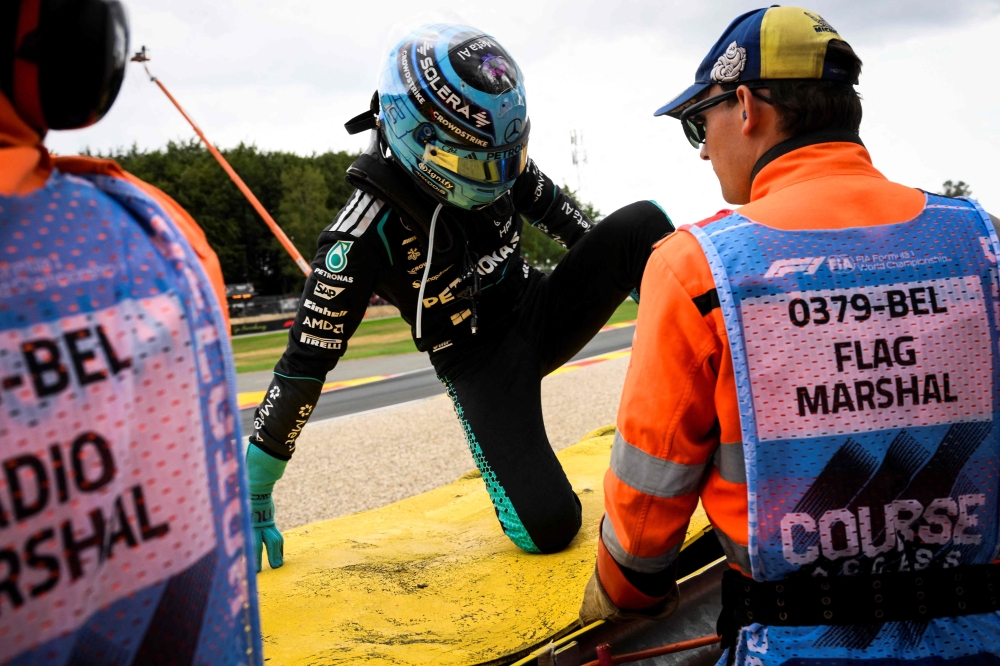 Mercedes' British driver George Russell reacts as he leaves the racing tack after crashing in gravels following a collision with Ferrari's British driver Lewis Hamilton during the first round in the Formula One Belgian Grand Prix at the Spa-Francorchamps circuit, in Spa, on July 19, 2026. (Photo by JOHN THYS / AFP)